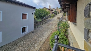 A cobblestone street in a historic town with stone buildings, a stone wall, and a wooden fence. - Apartamentos Gavín Biescas 3000 (Biescas)