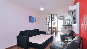 A living room with a black sofa, a small table, and a red accent wall. - MZapartments Raul Penthouse 06 (Rio de Janeiro)
