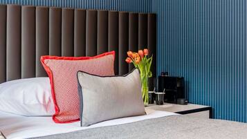 Una habitación de hotel moderna con una cama, una mesita de noche, un jarrón de tulipanes y una pared a rayas.