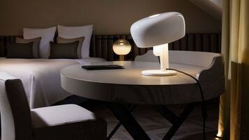 Une chambre d’hôtel moderne avec une table à manger ronde, une lampe blanche et un lit agrémenté de plusieurs coussins.