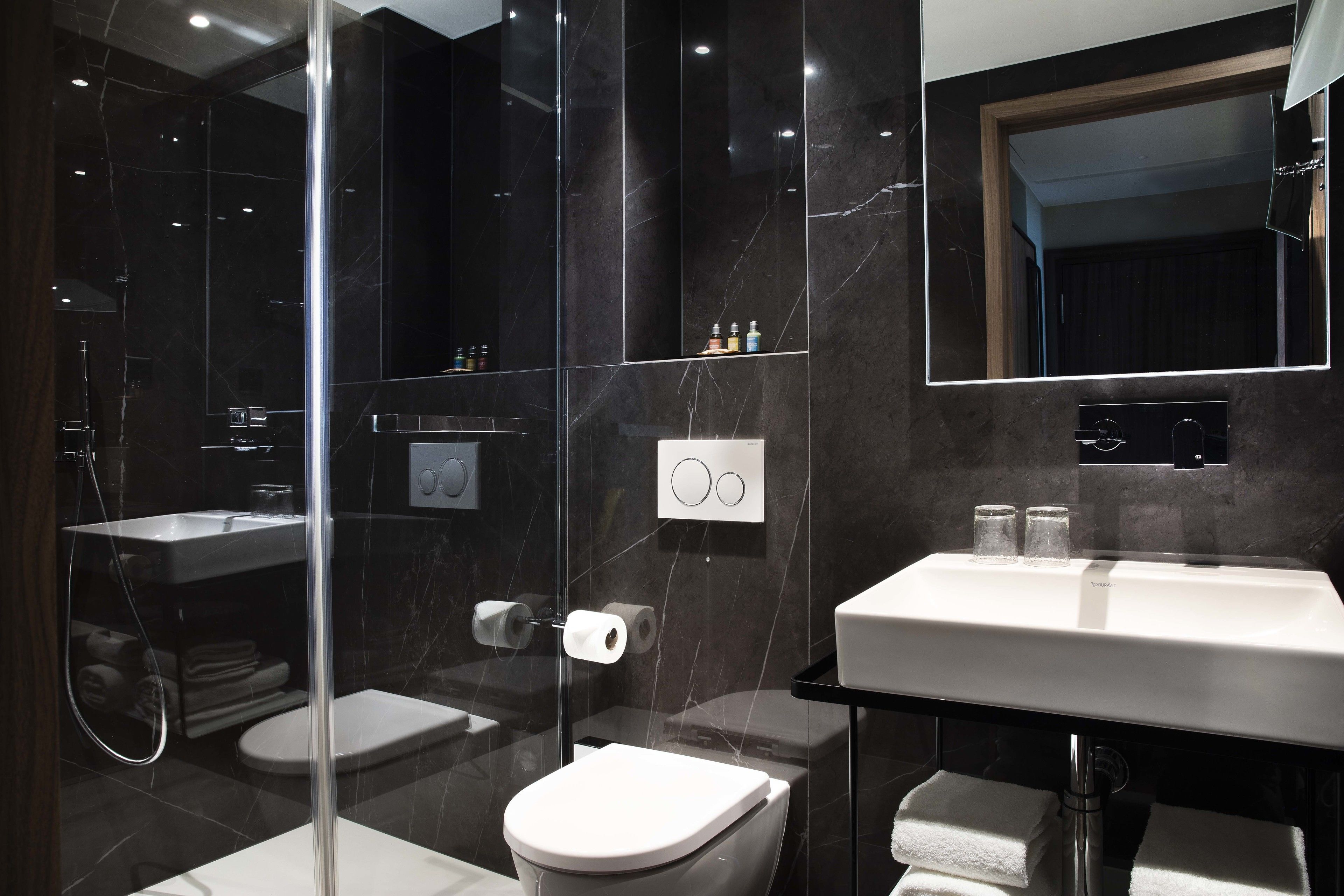 A modern bathroom with a glass-enclosed shower, a white toilet, and a vanity with a mirror.