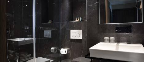 A modern bathroom with a glass-enclosed shower, a white toilet, and a vanity with a mirror.
