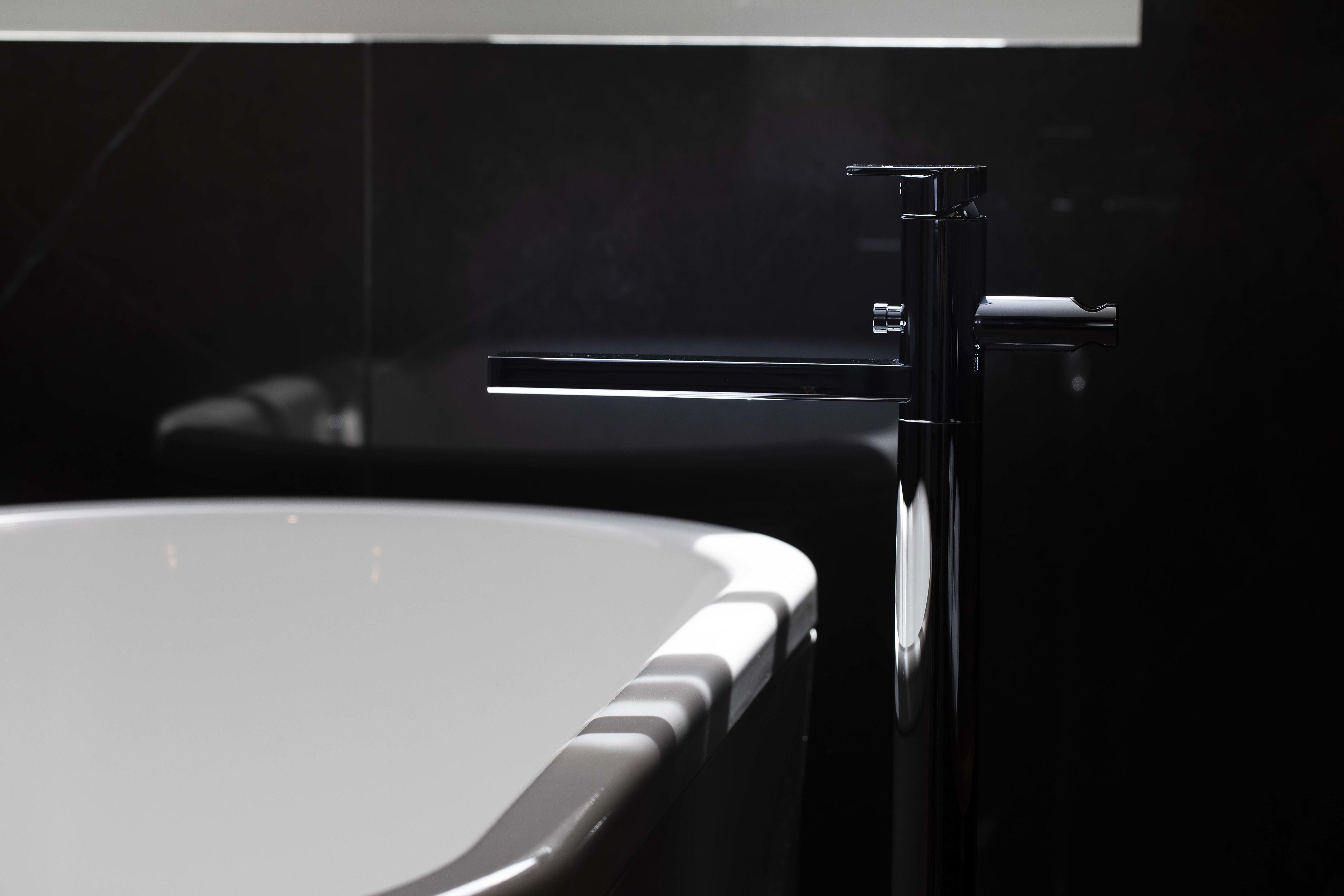 A modern bathroom with a sleek black bathtub and a chrome faucet.
