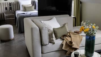 Una habitación de hotel moderna con sofá, mesa de centro, televisor y cama con cabecera.