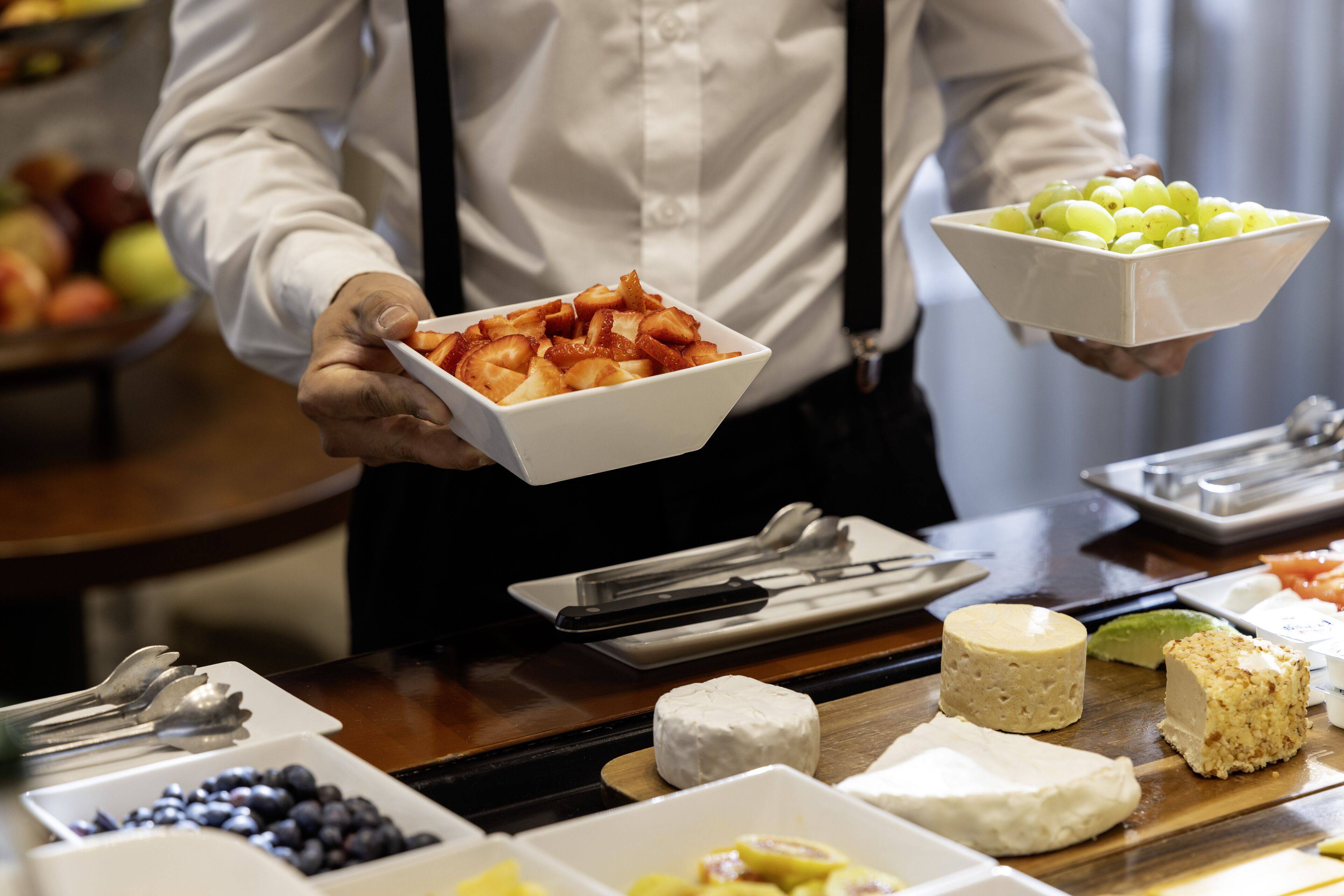 Un buffet proposant une variété d’aliments, notamment des fruits, des fromages et un saladier de raisins.