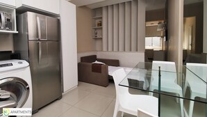 Eine moderne Küche mit einem Edelstahl-Kühlschrank, einer Waschmaschine und einem Glastisch mit weißen Stühlen.