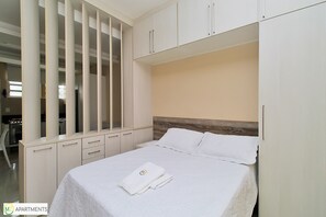 A bedroom with a bed, a wardrobe, and a desk.