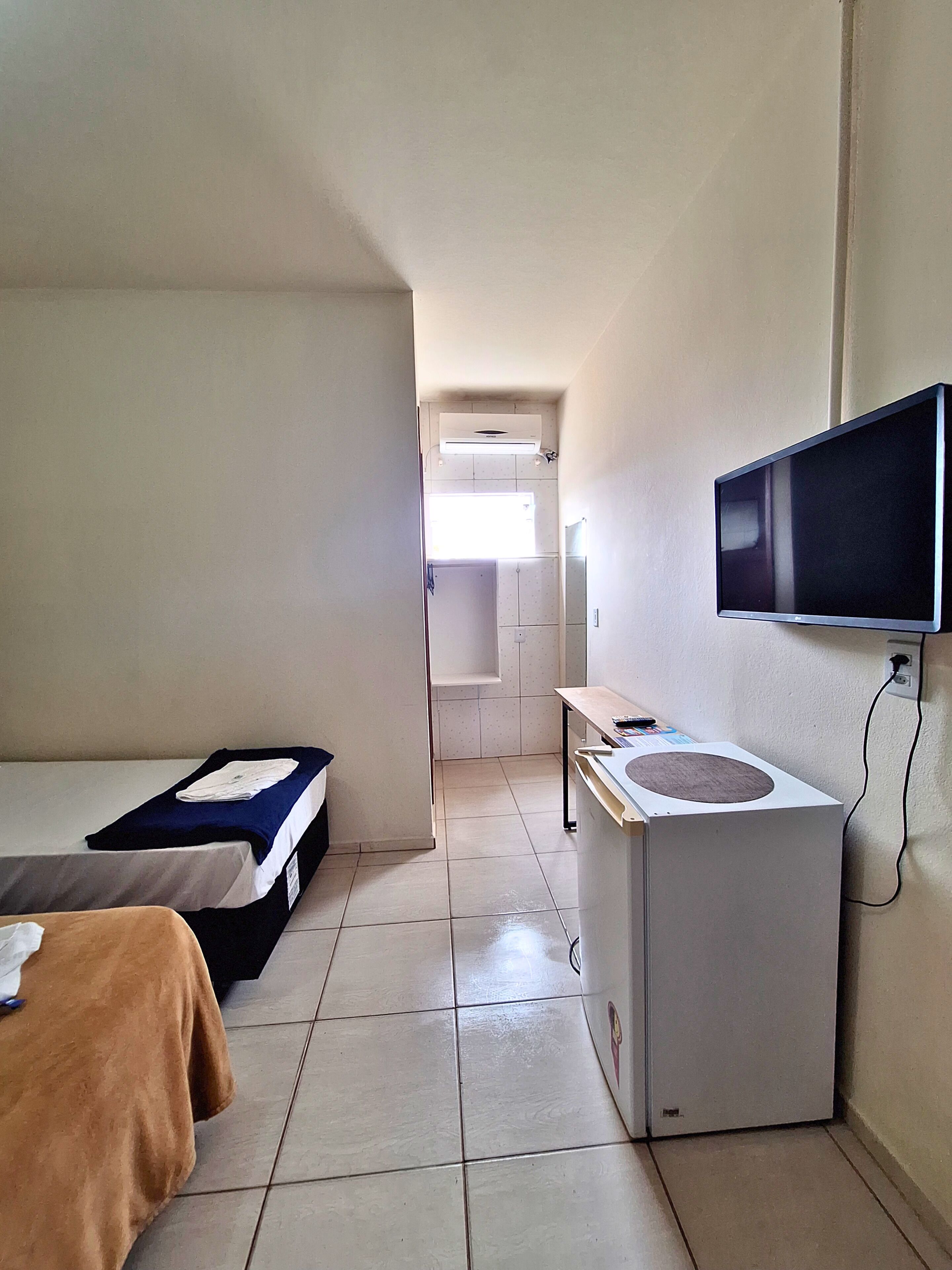 Habitación de hotel con dos camas, televisión, una mesita y lavadora.