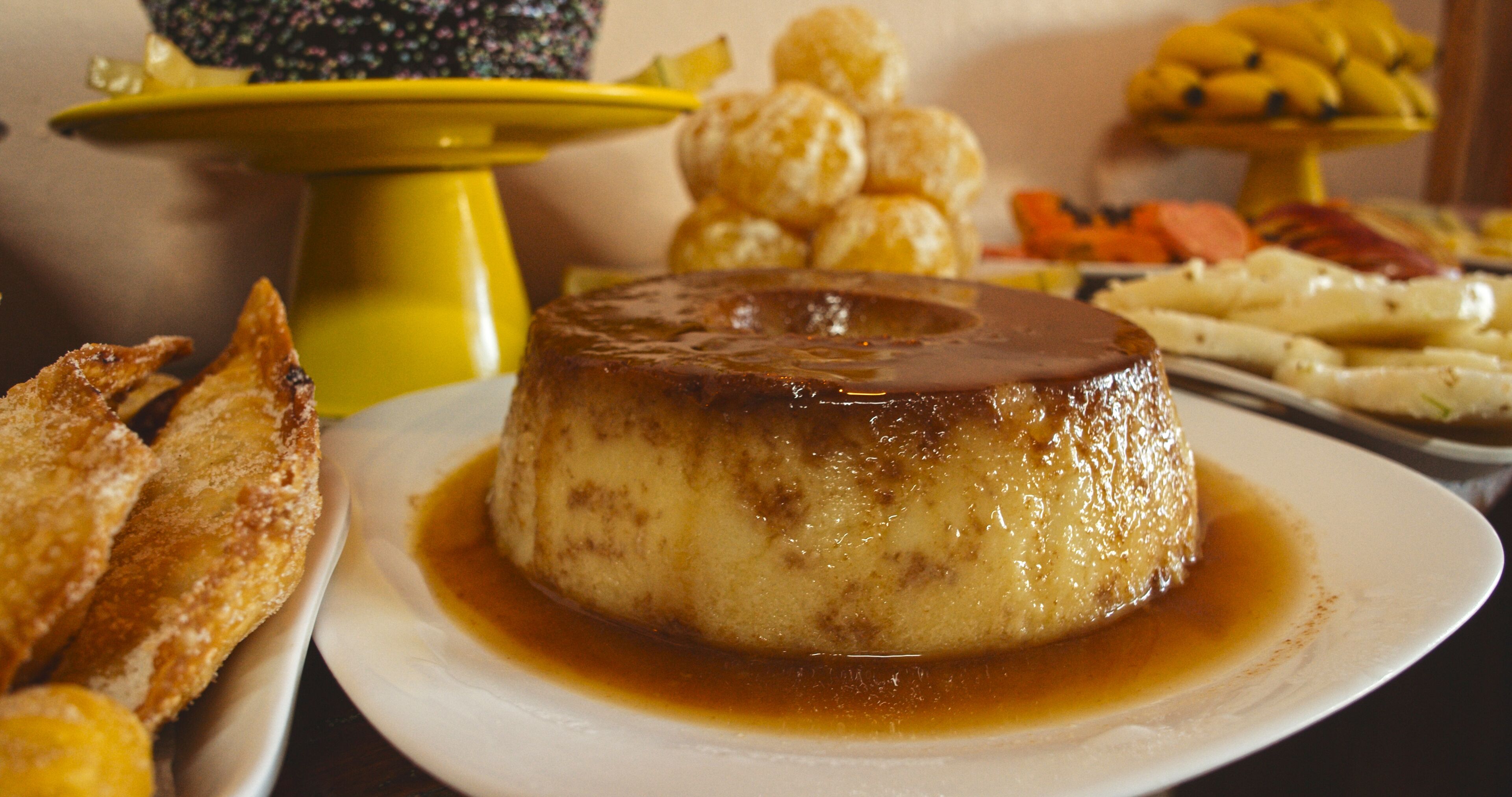 Un plat de postres amb un flà de caramel, acompanyat de pa i altres pastissos.