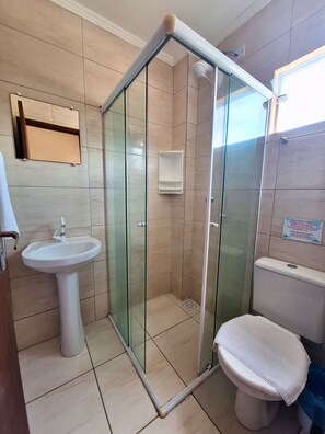 A bathroom with a glass-enclosed shower, a pedestal sink, and a toilet.