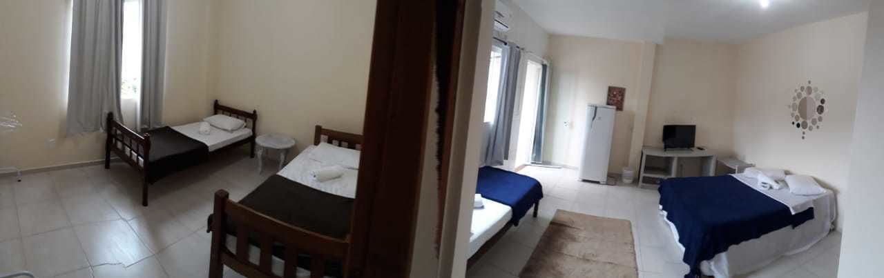 Ein Zimmer mit zwei Einzelbetten, einem kleinen Tisch, einem Stuhl, einem Schreibtisch mit Stuhl, einem Fernseher und einem Fenster mit Vorhängen.