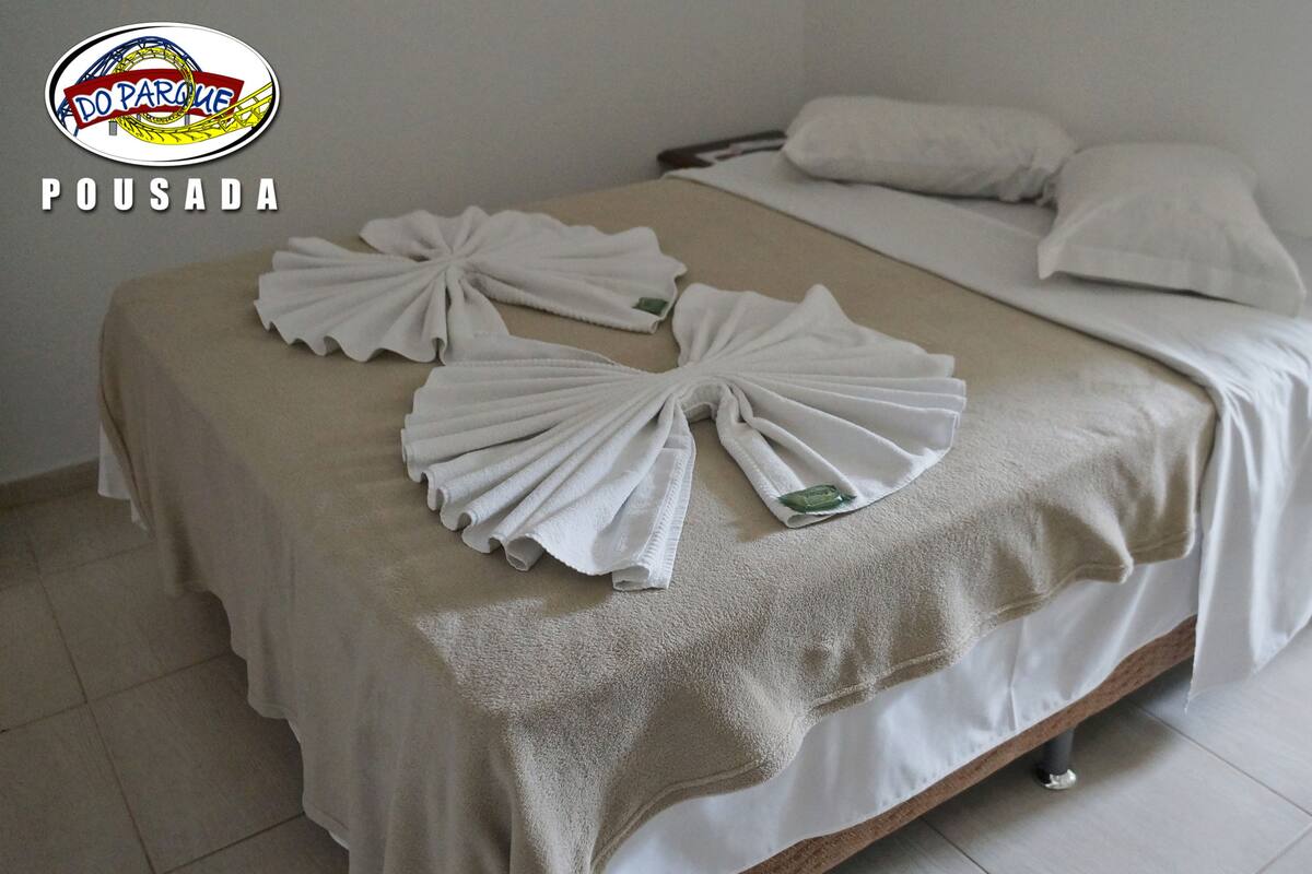 A hotel room with a bed, pillows, and towels arranged on the bed.