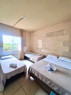 A hotel room with two beds, a large window, and a view of greenery outside. - Do Parque Pousada (Penha)