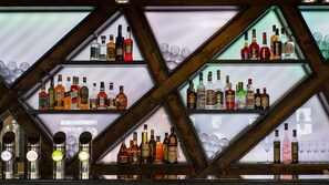 A bar with shelves of liquor bottles and glasses. - River Lodge (Vienna)