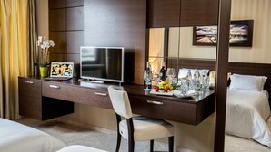A hotel room with a large desk, a television, a chair, a bed, and a mirror. - River Lodge (Vienna)