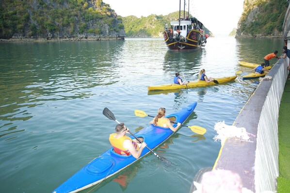 A group of people kayaking on a calm river with a boat in the background. - Sunlight Cruise (Hai Phong)