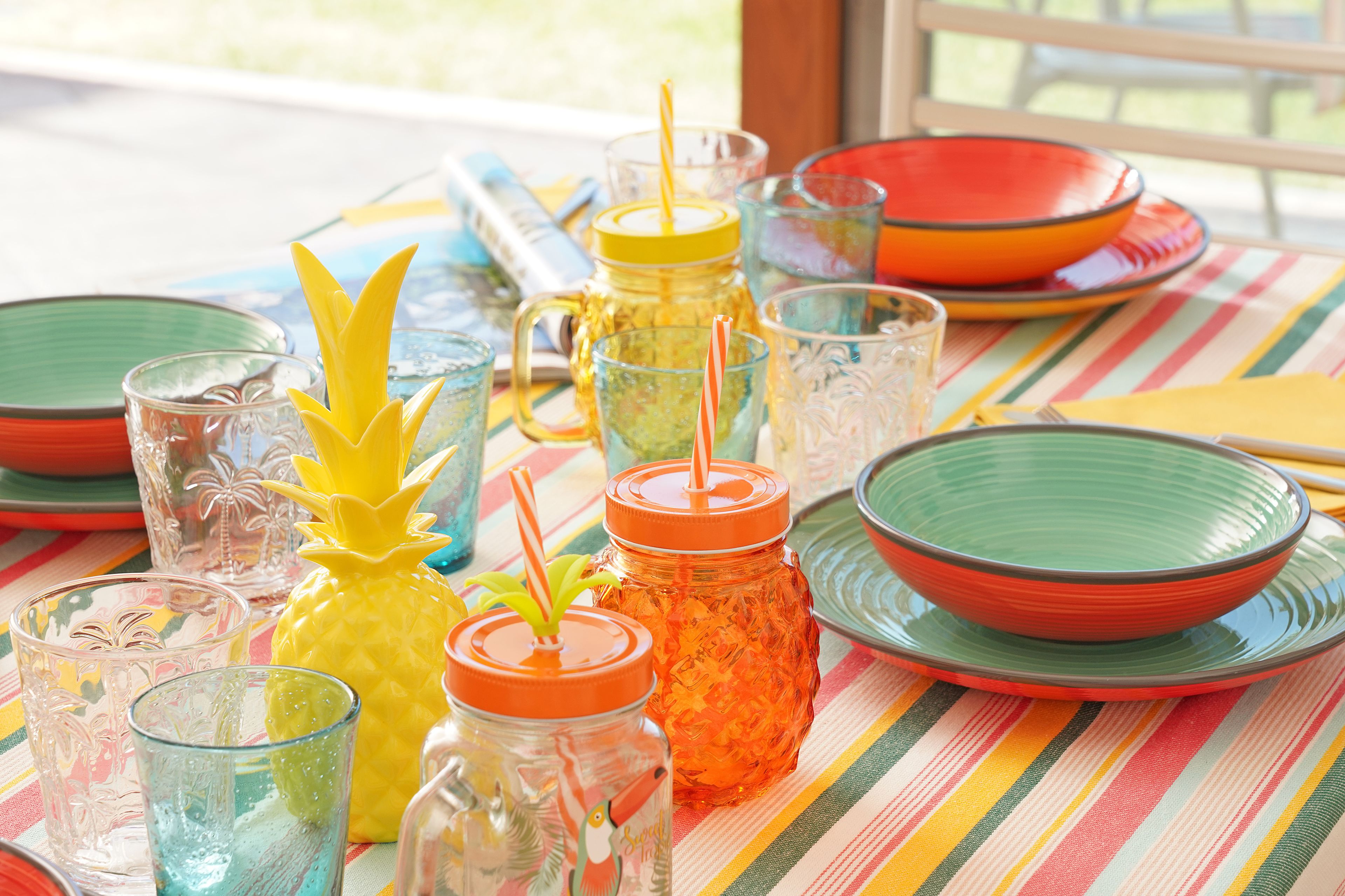 A table with various glassware and colorful plates, suggesting a dining setting.