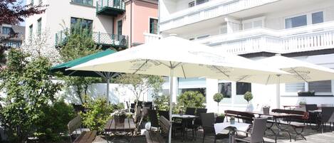 An outdoor patio with tables and chairs, surrounded by buildings.
