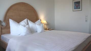 A neatly made bed with a wooden headboard and white bedding.