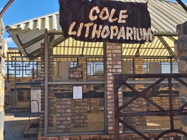 A rustic metal gate with a sign reading 'COLE LITHOPARIUM' and a sign indicating 'LITHOPS OF NAMIBIA'. - Alte Kalkofen Lodge (Simplon)