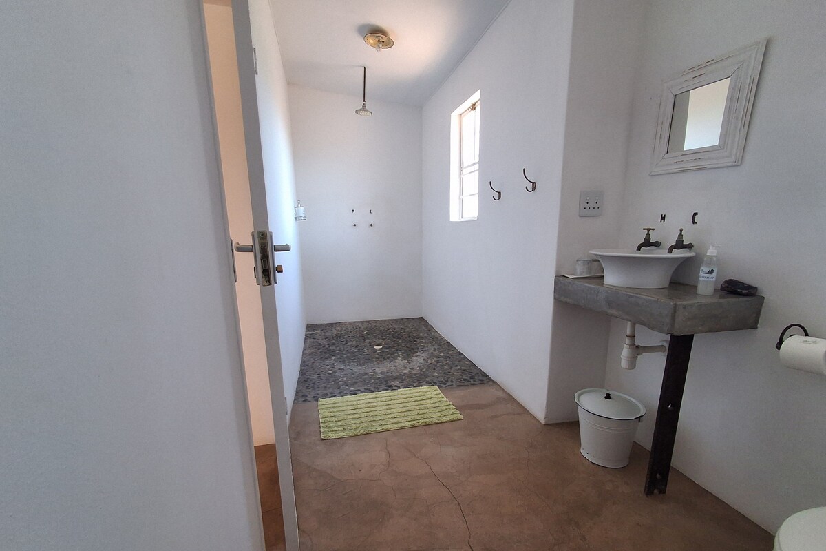 A bathroom with a sink, mirror, and toilet. There is a towel rack and a small window.
