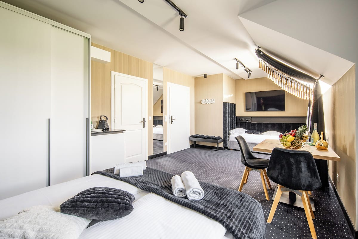 A hotel room with a bed, a desk with a chair, a TV, and a dining area.