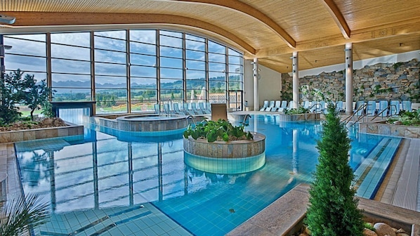 A large indoor swimming pool with multiple lanes, surrounded by lounge chairs and a stone wall. - Aparthotel Diamond SPA Relax (Bukowina Tatrzanska)
