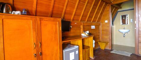 A wooden cabin interior with a kitchenette, a sink, and a television.