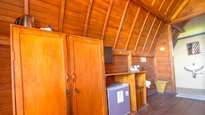 Interior de una cabaña de madera con techo de madera, un refrigerador, un lavamanos y un armario.