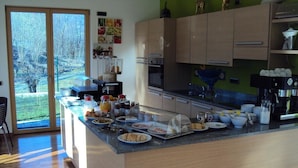 Een moderne keuken met een groot eiland, houten kastjes en uitzicht op een tuin via glazen deuren.