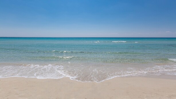 Una playa con aguas azul turquesa y una orilla arenosa.