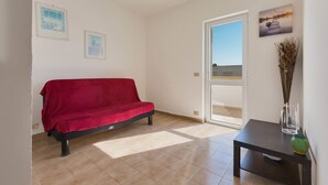 Una habitación con un sofá rojo, una mesita con un florero y dos cuadros en la pared.