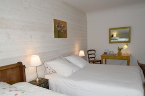 A bedroom with a wooden headboard, two beds, a nightstand, a chair, a small table with a lamp, and a mirror on the wall. - Chambre d'hôtes Ty Eleana (Concarneau)