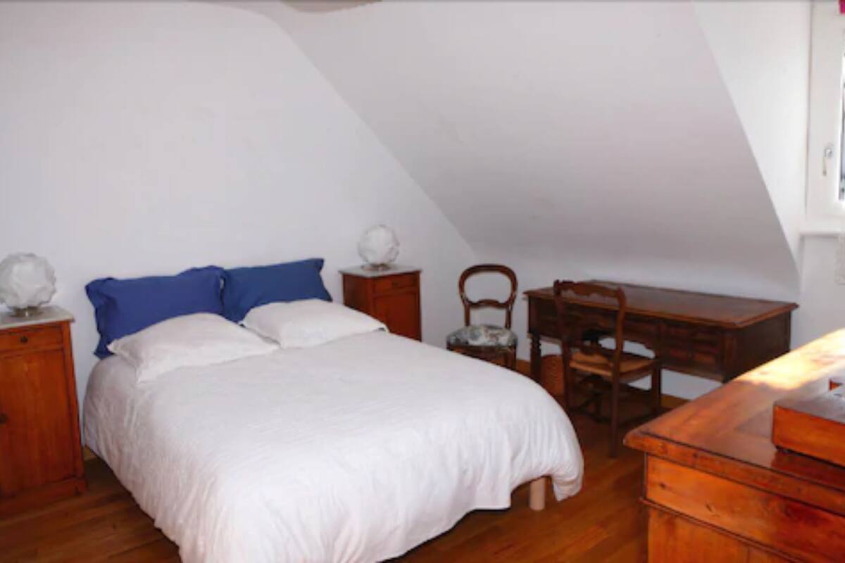 Een slaapkamer met een bed, een houten bureau, een stoel en een kledingkast.