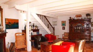 Ein Wohnzimmer mit Holztisch, roten Stühlen, einer Treppe und einem Schrank mit Glastüren.