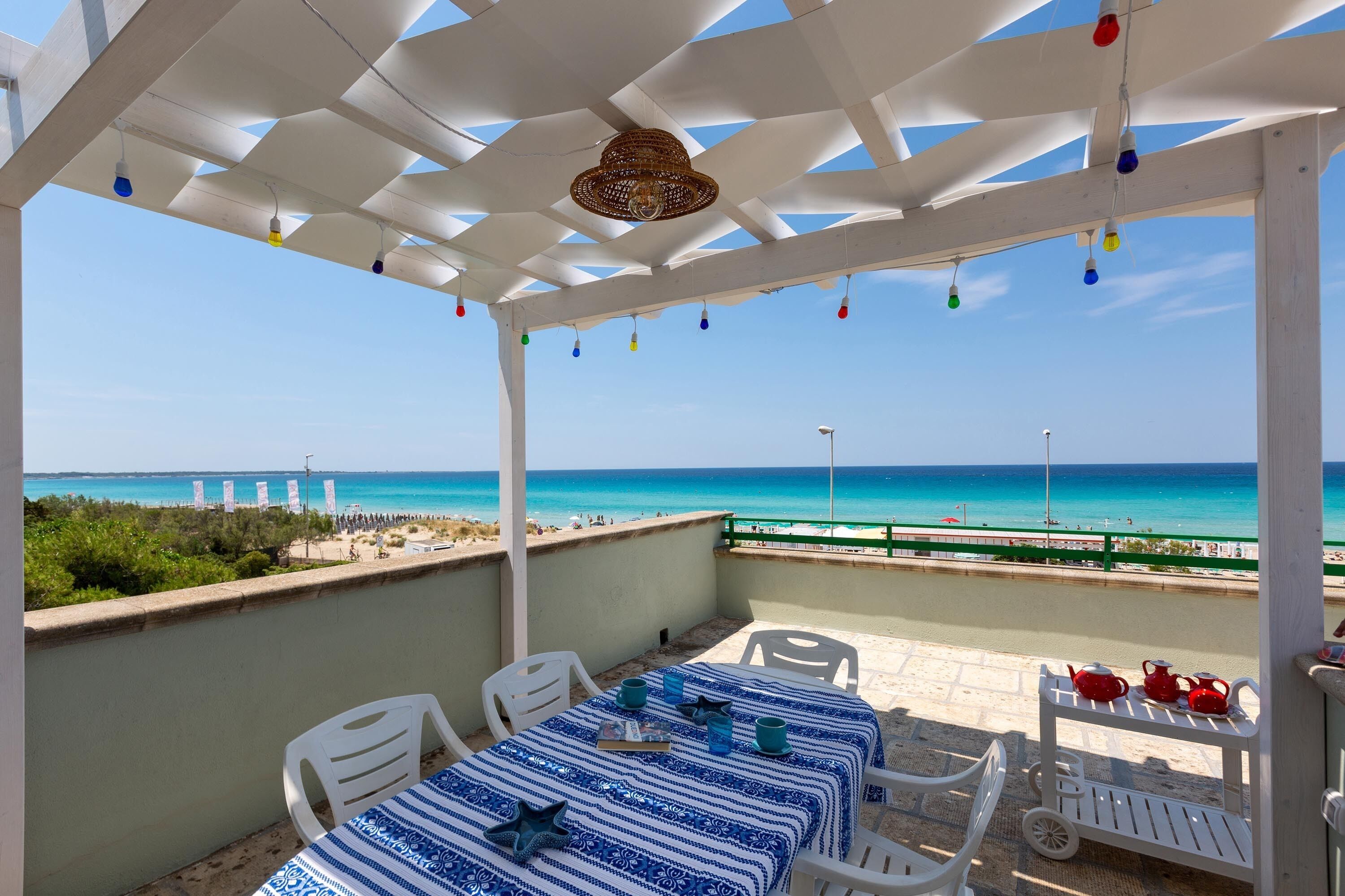 A covered outdoor seating area with a view of the beach and ocean.