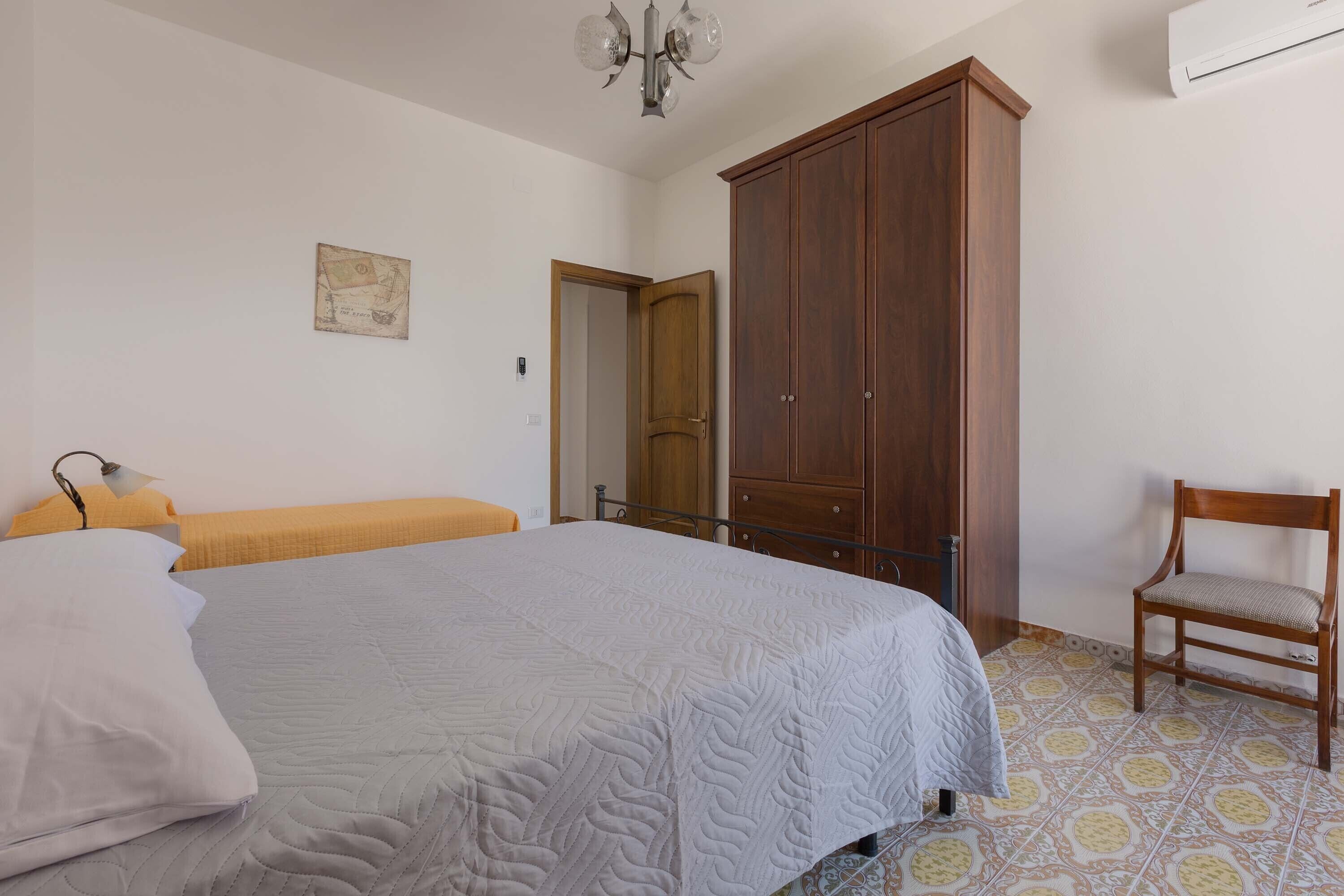Ein Schlafzimmer mit einem Bett, einem Holzschrank, einem Stuhl und einem kleinen Tisch.