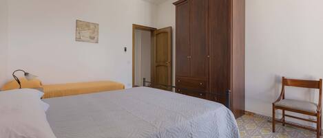 Ein Schlafzimmer mit einem Bett, einem Holzschrank, einem Stuhl und einem kleinen Tisch.