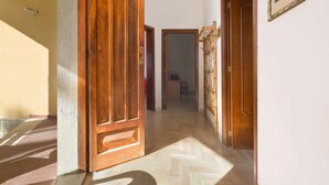 A hallway with a wooden door, a bamboo screen, and a framed picture on the wall. - Appartamento Sabbia Chiara (Porto Cesareo)