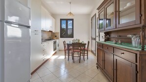 A kitchen with a refrigerator, stove, and dining table with chairs. - 984 Appartamento Solaris by Barbarhouse (Nardò)