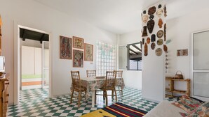 A room with a checkered floor, a dining table with chairs, a sofa, and a wall with various decorative items. - Attico La Baia (Gallipoli)
