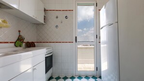 A compact kitchen with white cabinets, a checkered floor, and a door leading outside. - Attico La Baia (Gallipoli)