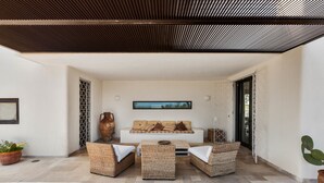 A modern outdoor seating area with wicker furniture, a sofa with cushions, and a large vase.