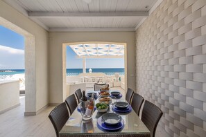 A dining area with a table set for four, overlooking a beach.