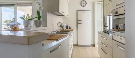 Una cocina moderna con una isla grande, armarios blancos y un reloj en la pared.