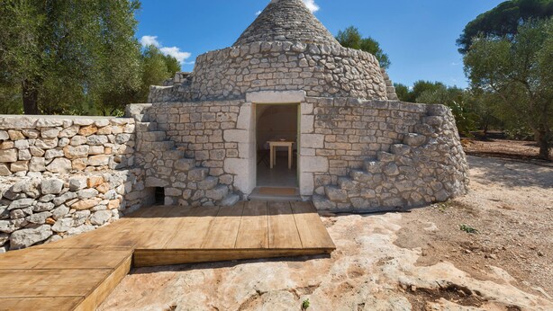 Une construction dotée d’un toit en pierre, d’une entrée en bois et d’une rampe menant à l’intérieur.
