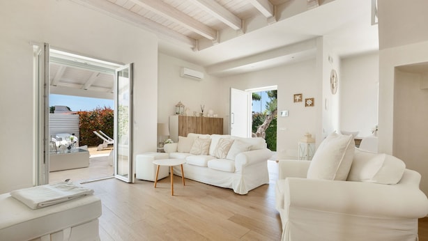 A spacious living room with a white sofa, a coffee table, and a sliding glass door leading to an outdoor area. - Villa Adele (Maruggio)