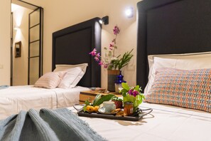 Ett hotellrum med två sängar, ett bricka med frukosttillbehör och en vas med blommor.