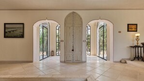 Un vaste hall d’entrée doté d’une porte cintrée au centre, d’un sol carrelé et d’œuvres d’art encadrées accrochées aux murs.