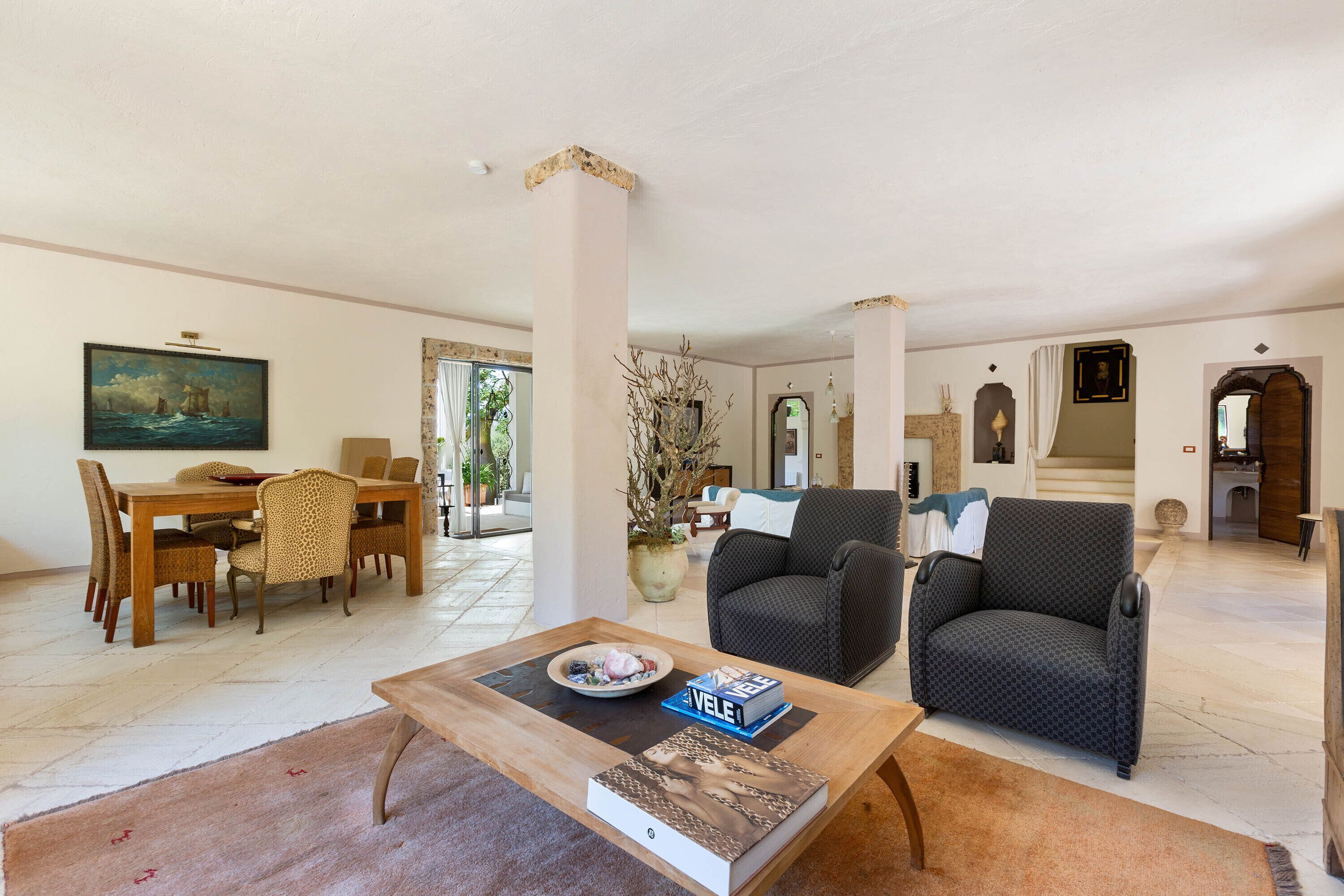 A spacious living room with a wooden coffee table, a sofa, and a dining area with a table and chairs.